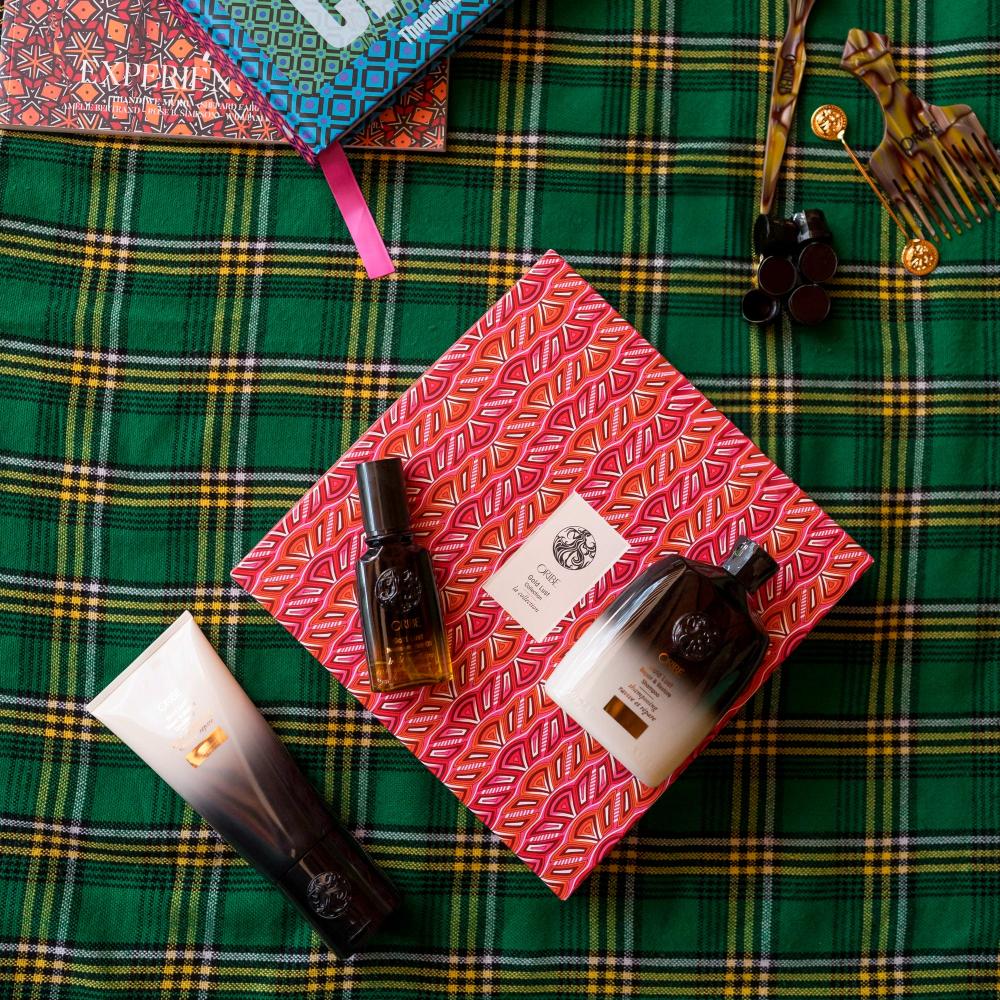 Green and yellow flannel print with Gold Lust Shampoo, Conditioner and Hair Oil alongside red patterned gift box packaging 