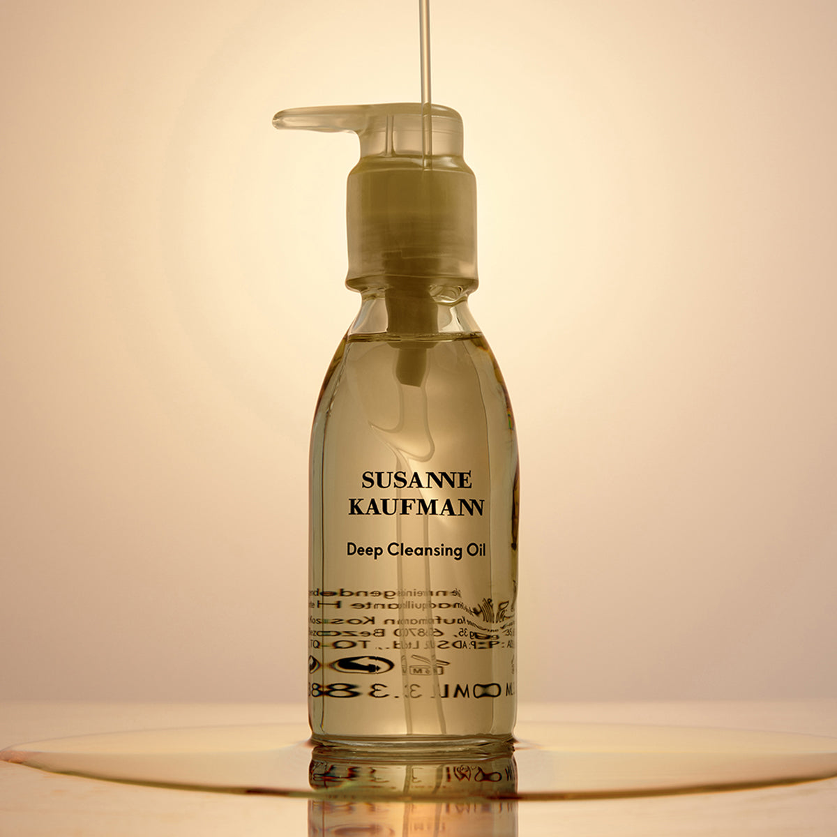 Bottle of Susanne Kaufmann Deep Cleansing Oil on a reflective surface with a warm background