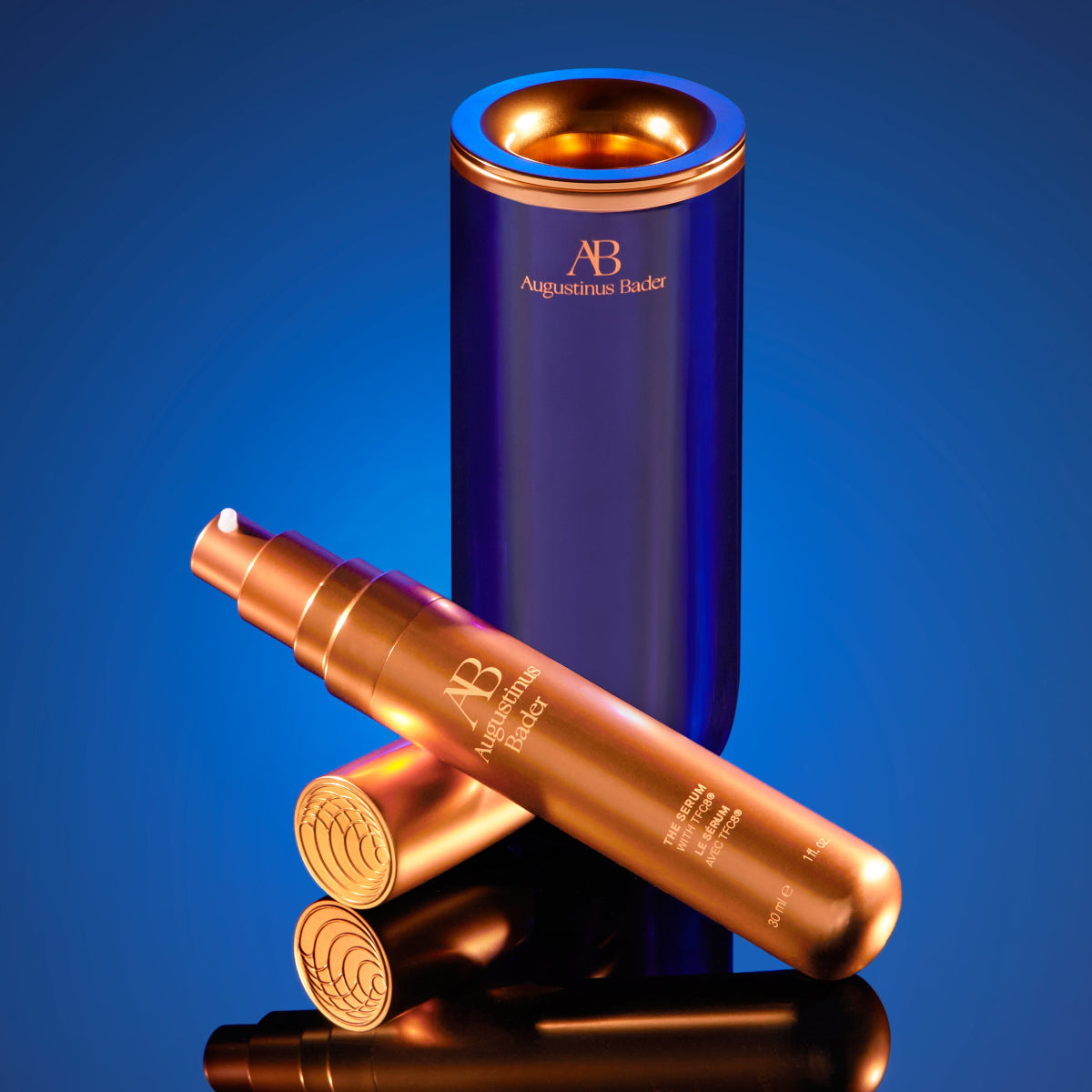 Blue and bronze cosmetic containers with 'AB' branding on a blue background
