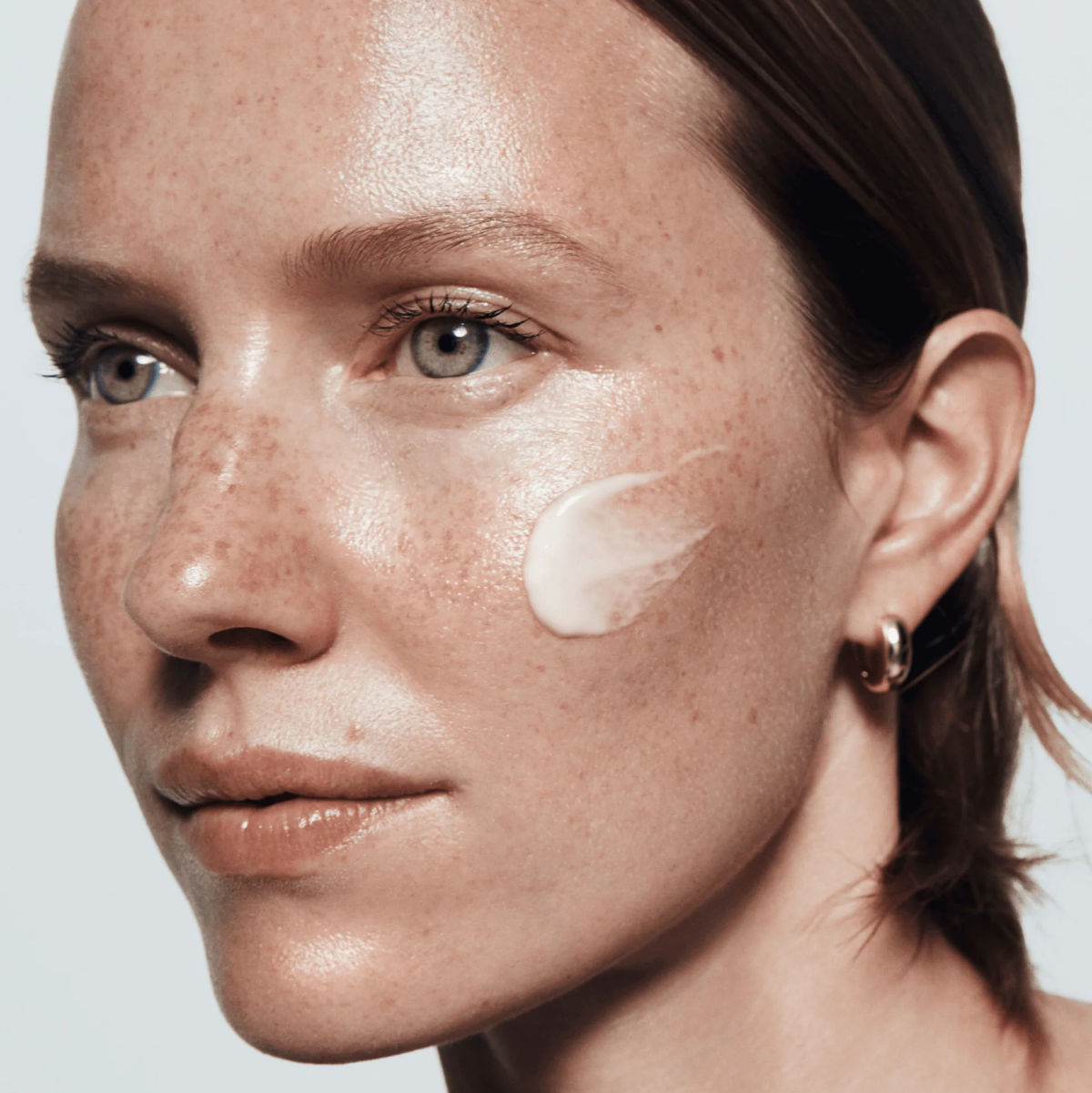 Close-up of a person with skincare product applied to their face against a neutral background