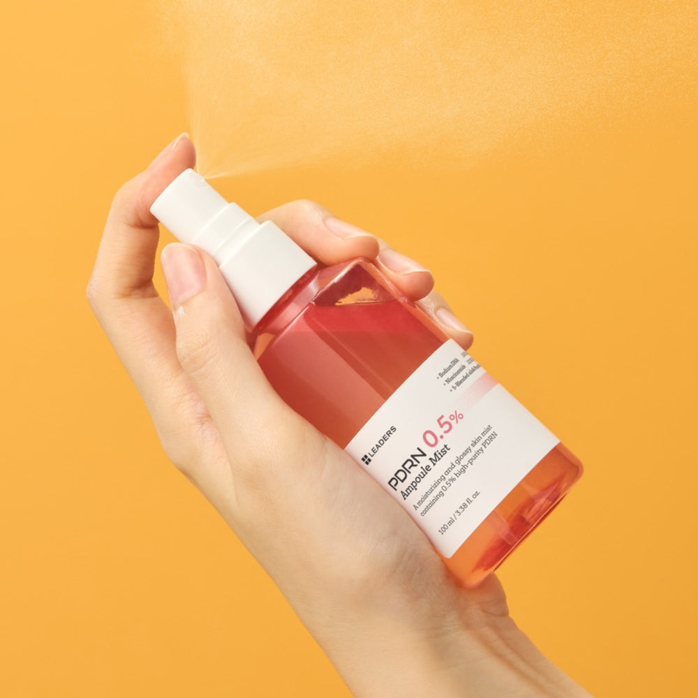 Hand holding a bottle of PDOEN Q.5% solution against an orange background