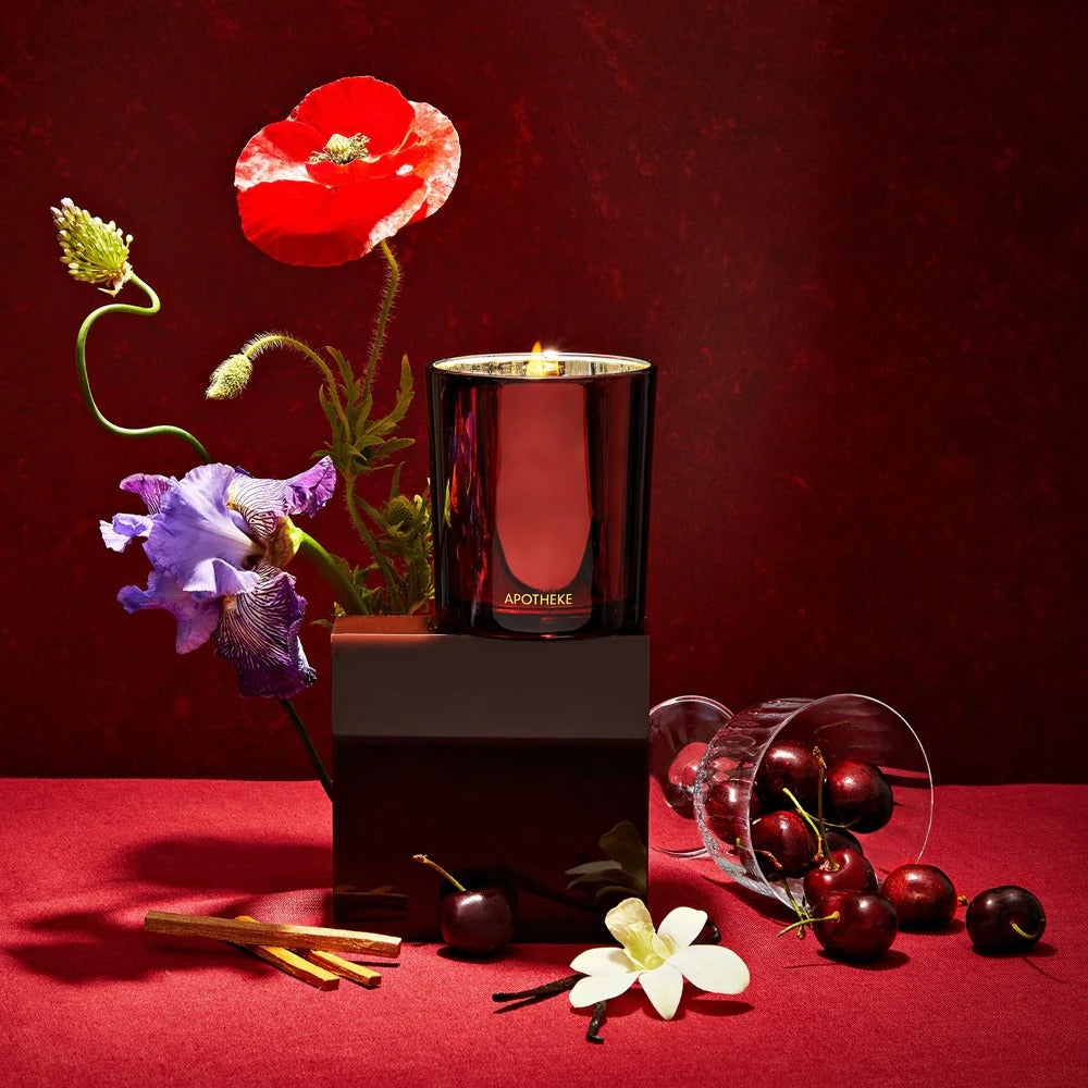 Apotheke candle with flowers and cherries on a red surface