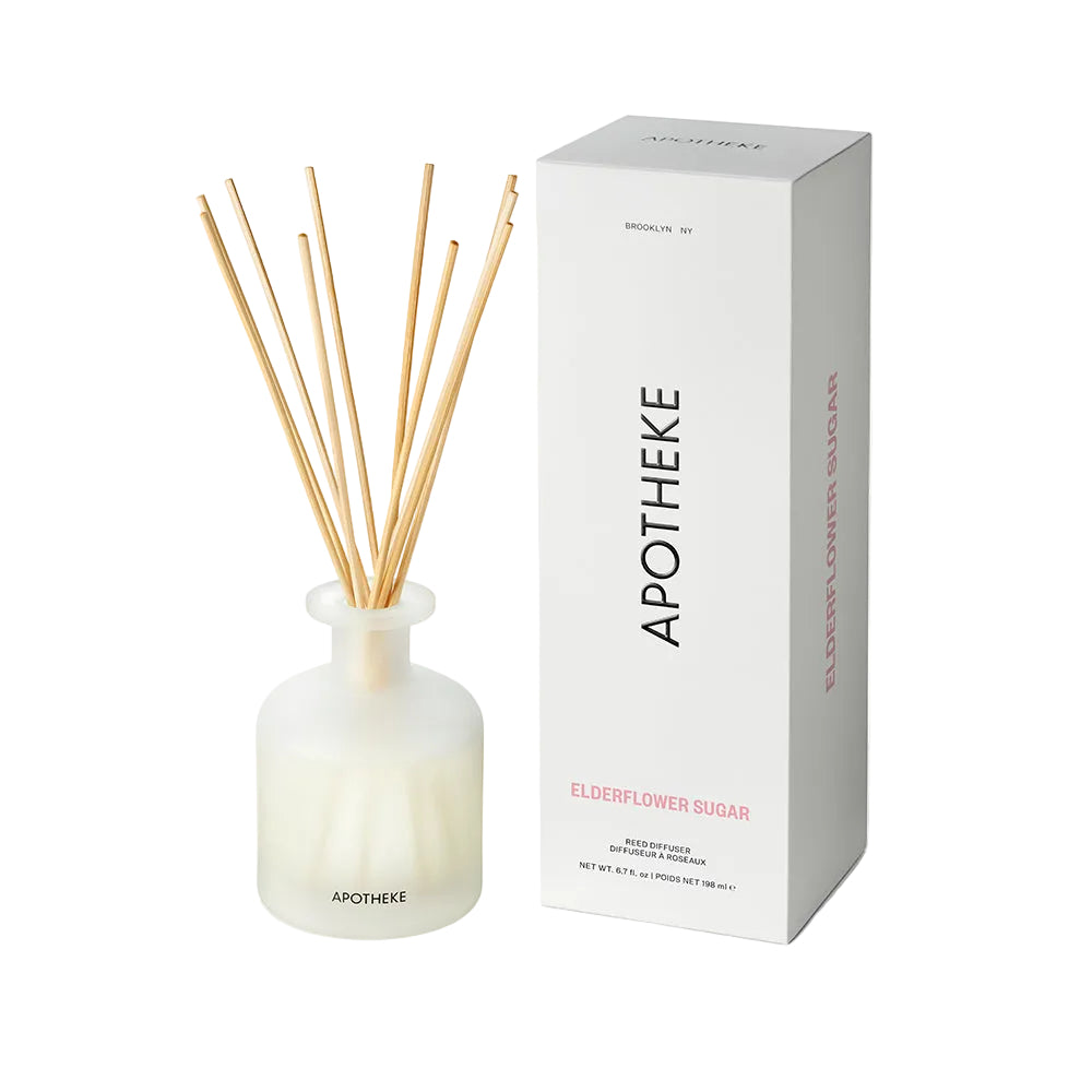 A reed diffuser bottle with natural reed sticks next to its white packaging box, both labeled 'APOTHEKE' and 'ELDERFLOWER SUGAR', on a clean white background.