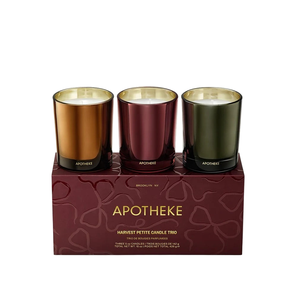 Three candles in metallic containers on a decorative Apotheke box.
