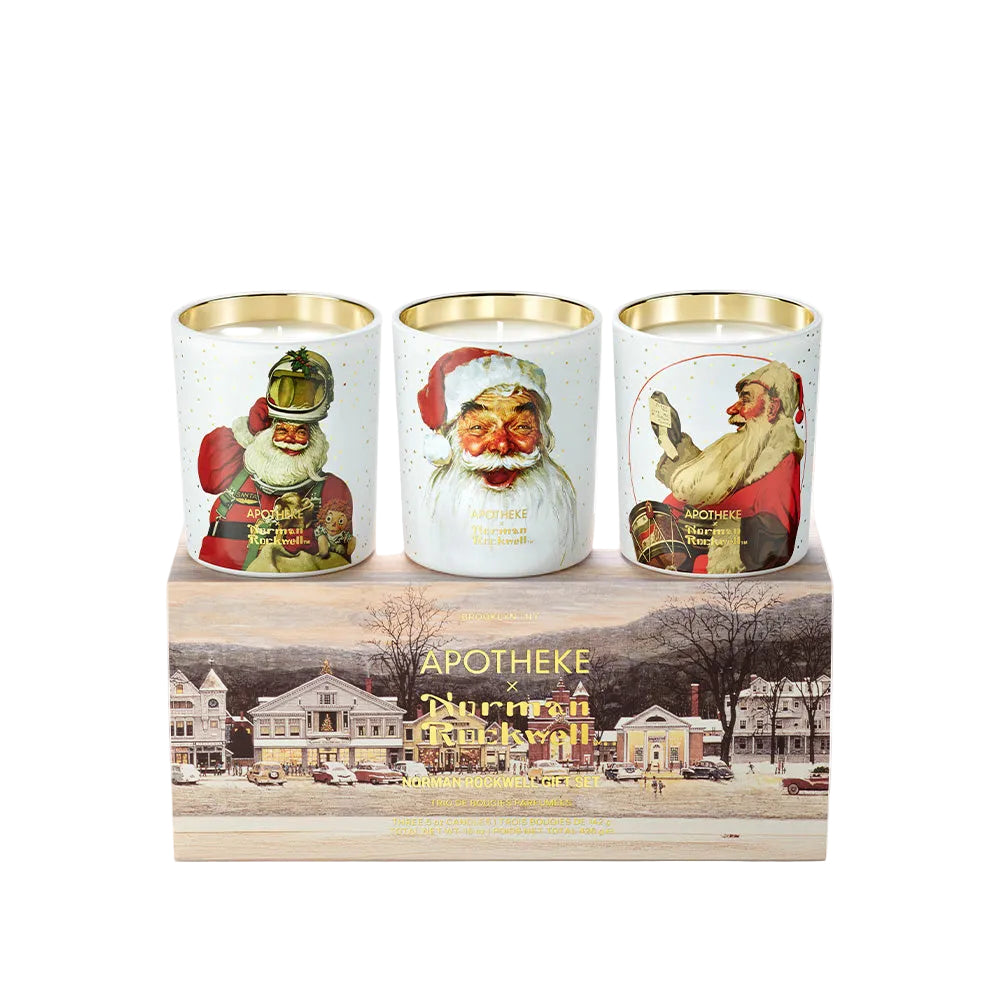 Three Apotheke  holiday-themed scented candles in white glass jars with gold rims, displayed on top of a printed wooden gift box. The candles feature vintage illustrations of Santa Claus in different outfits and poses.
