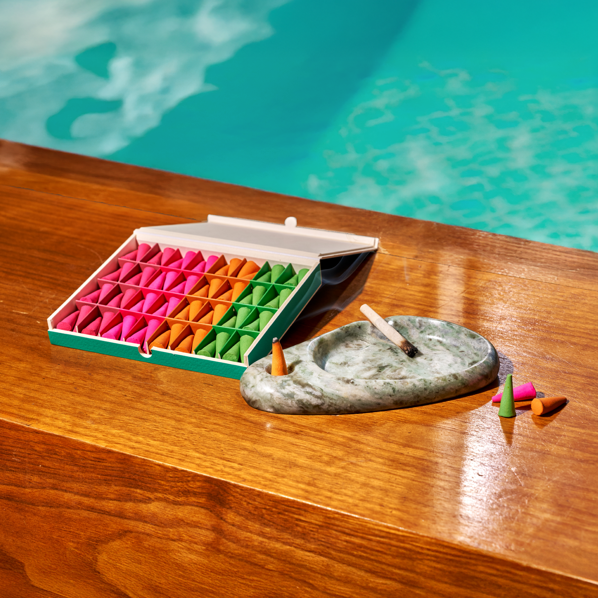 Houseplant By Ripple+ Ash & Scent Set ripple droplets and ashtray on a wood surface in front of blue water.