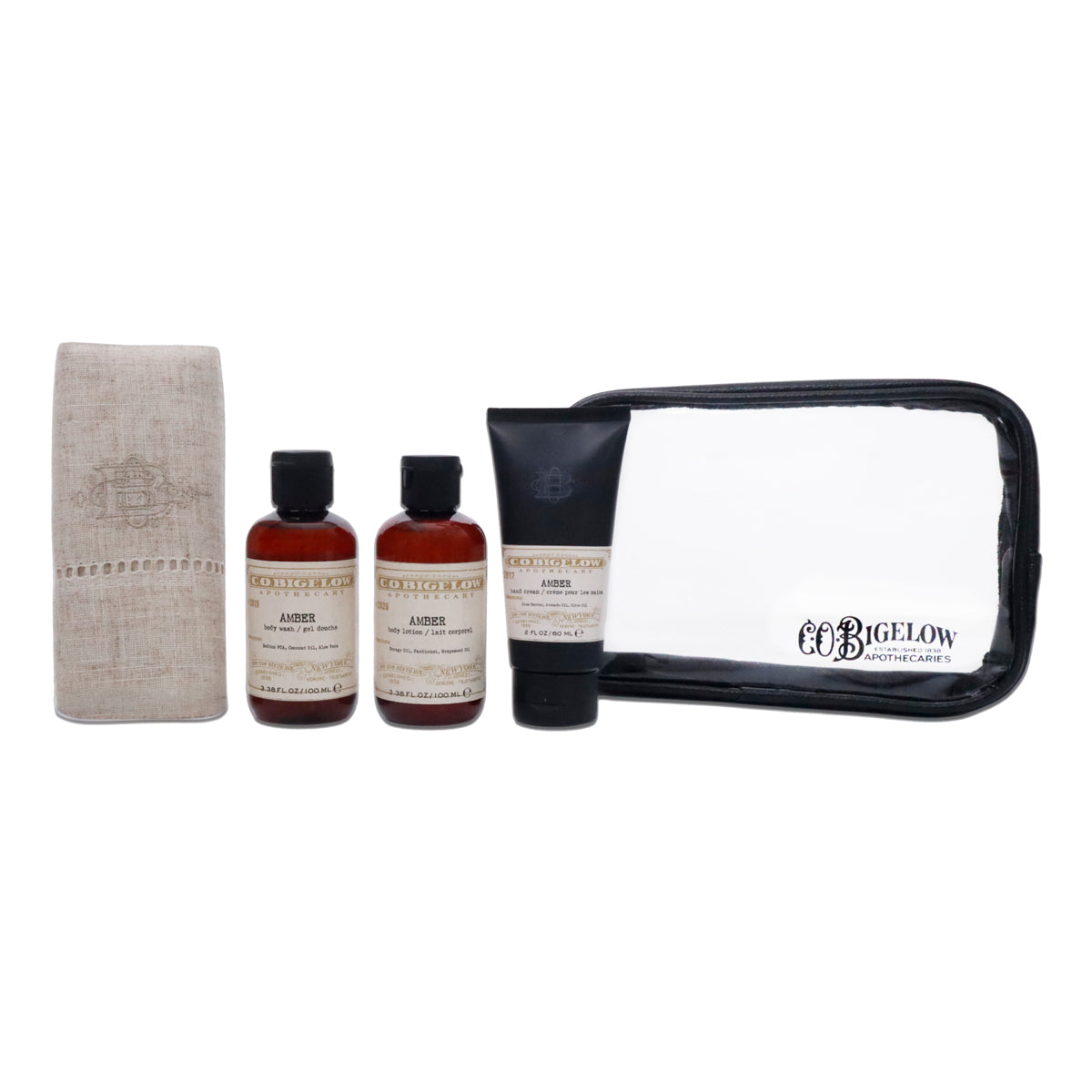 A 4-piece toiletry gift set by Bigelow on a white background, including a beige linen towel, two amber bottles of shower gel, a black tube of body wash, and a clear zippered pouch with a black trim.