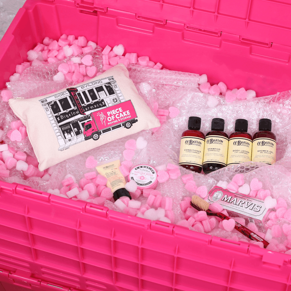 Pink storage bin filled with bubble wrap and various beauty products, including bottles and a tube.