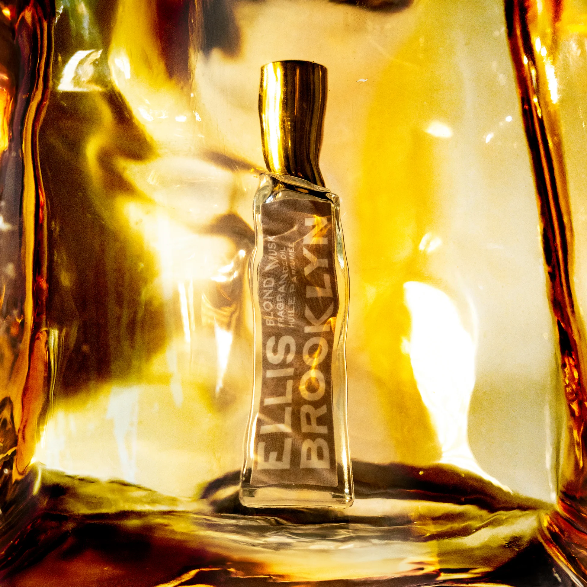 Ellis Brooklyn Blond Musk bottle distorted through amber