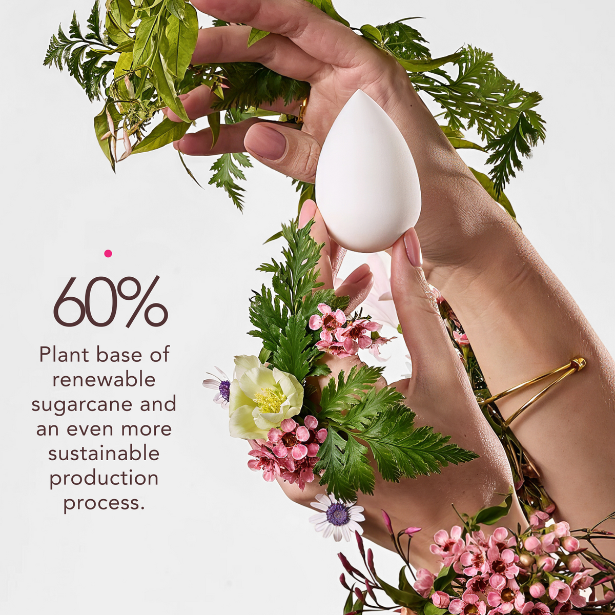 Hand holding a white tear drop sponge with greenery and flowers in the background, promoting a sustainable product.