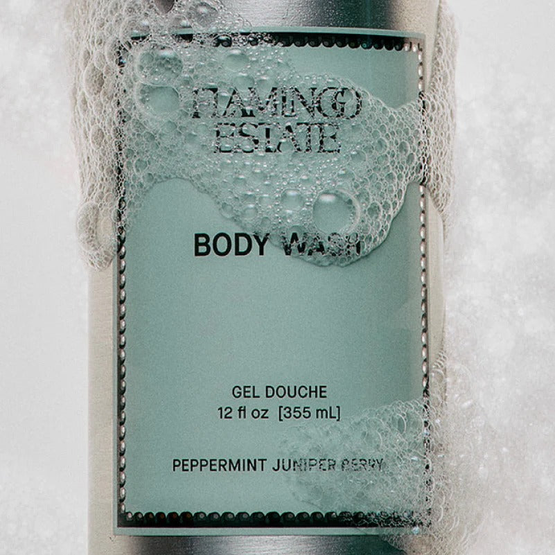 Body wash bottle with 'Flamingo Estate' branding and visible foam.