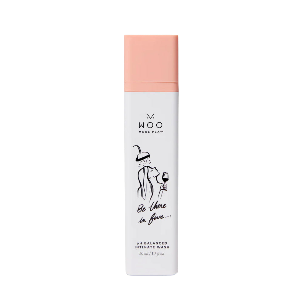 A white cylindrical bottle of WOO More Play Intimate Wash with a peach-pink cap, featuring a minimalist black line art illustration of a couple and the text 'Be there in five.