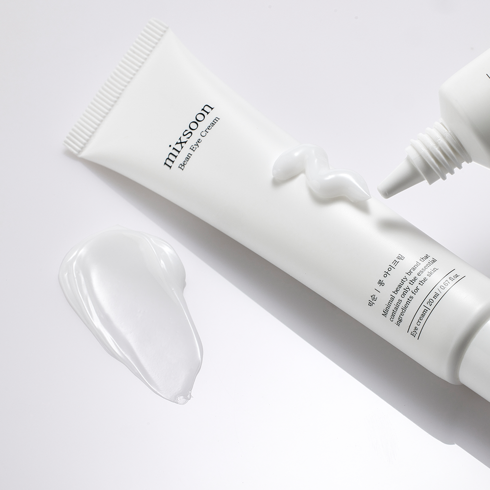 A white squeeze tube of mixsoon Bean Eye Cream with a smear of the cream in front, photographed on a clean white background.
