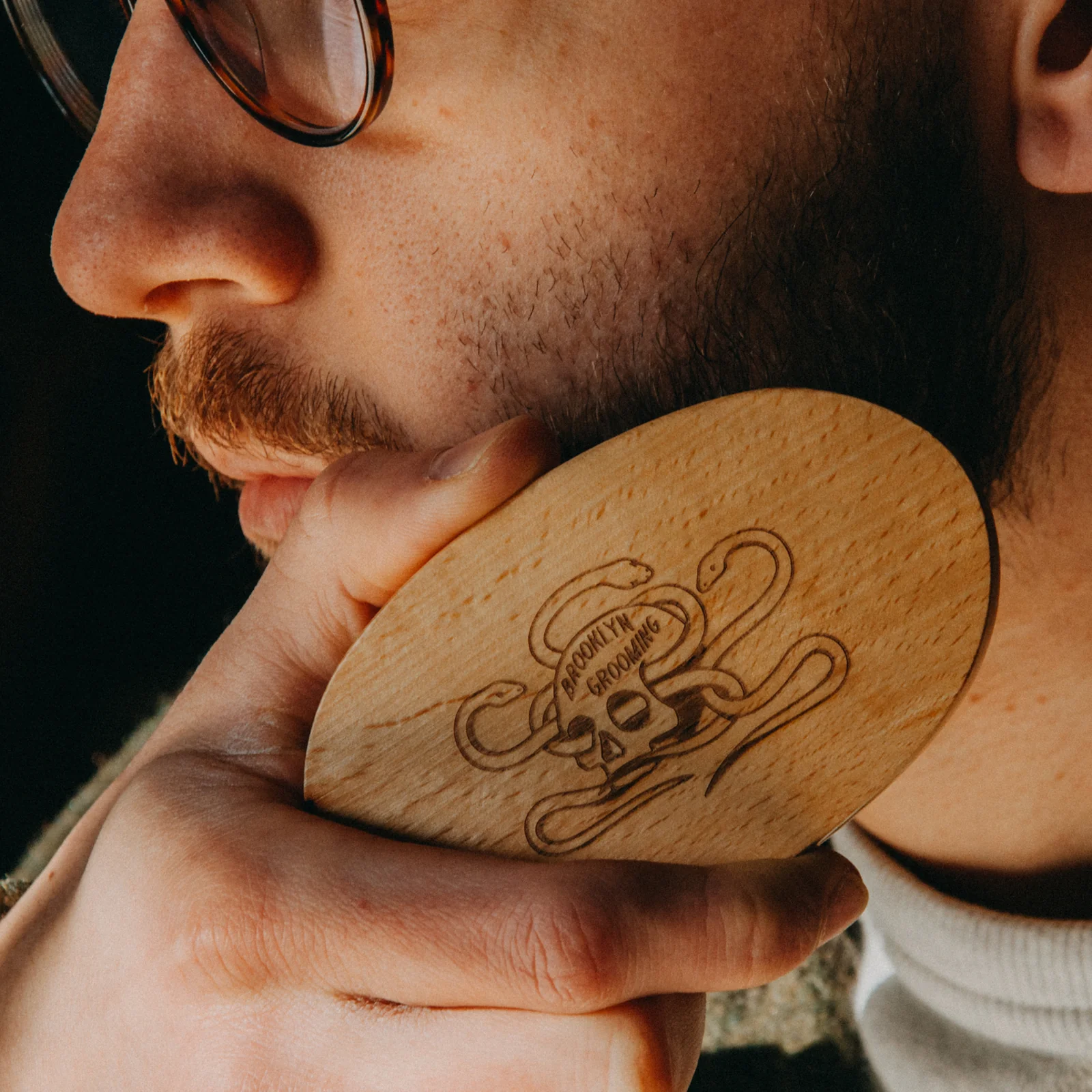 Man holding a wooden brush with a logo, close-up of face and brush.