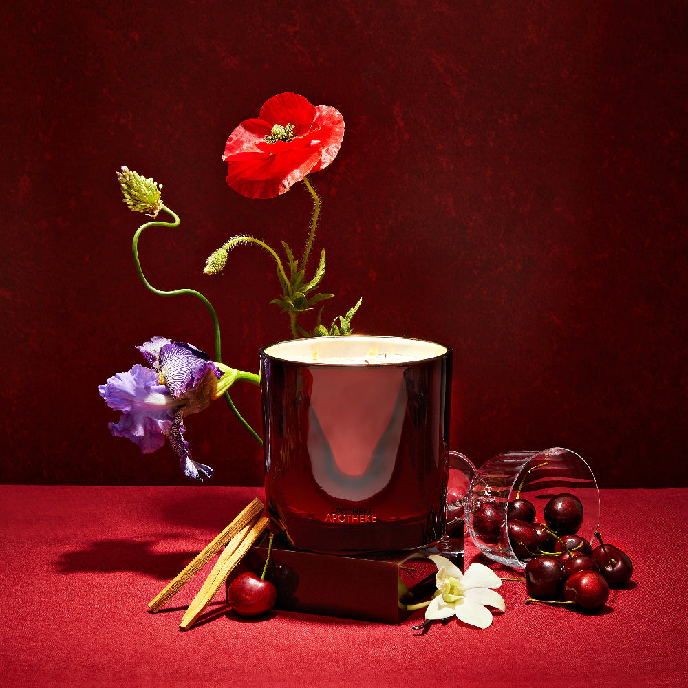 Red candle with flowers and fruits on a red background