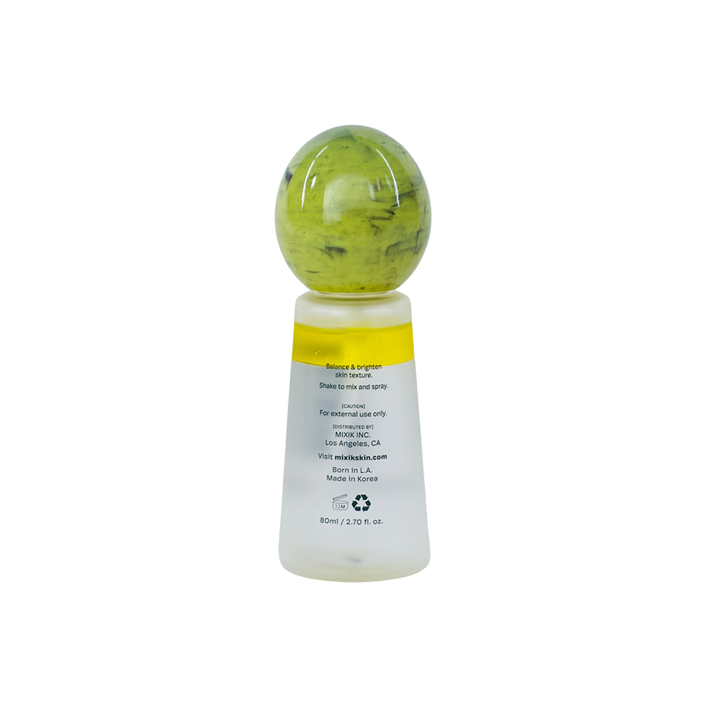 A small skincare bottle with a translucent frosted white body, a yellow band near the top, and a rounded green cap, shown on a plain white background.