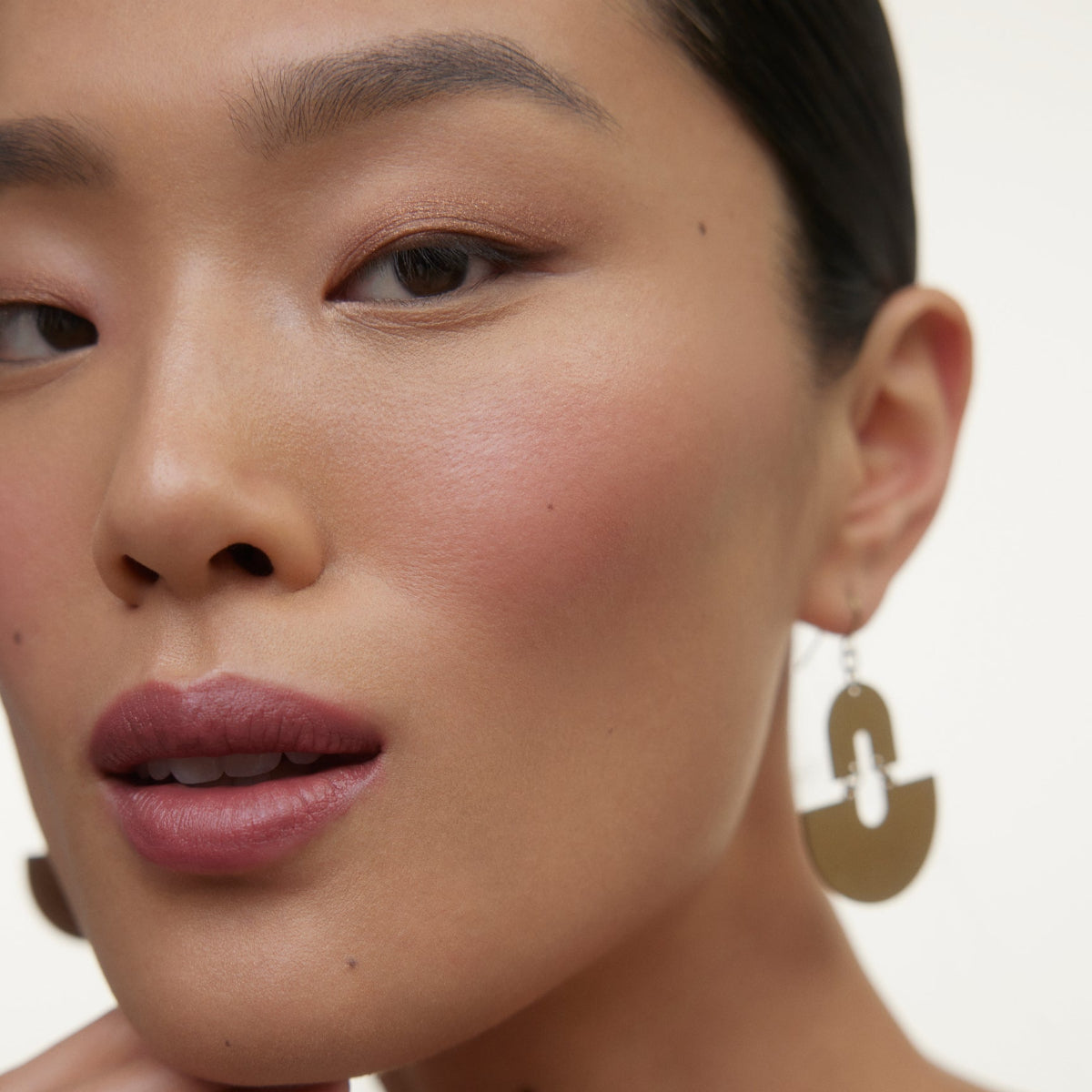Closeup of woman's face wearing Wonderblush makeup products. 