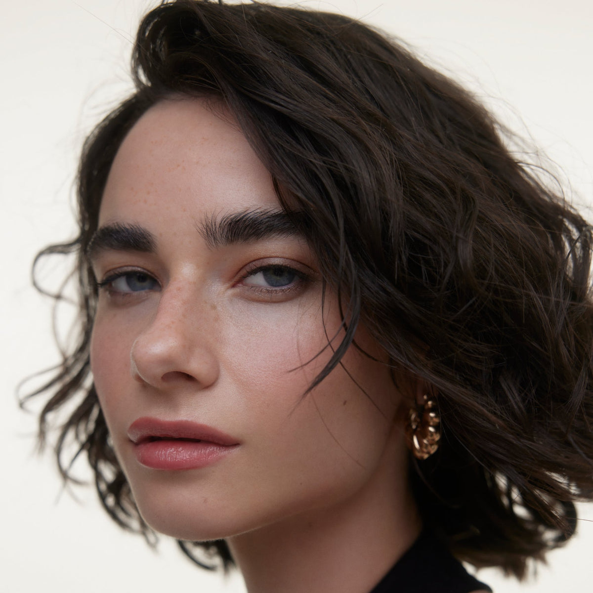 Closeup of woman's face wearing Wonderblush makeup products. 