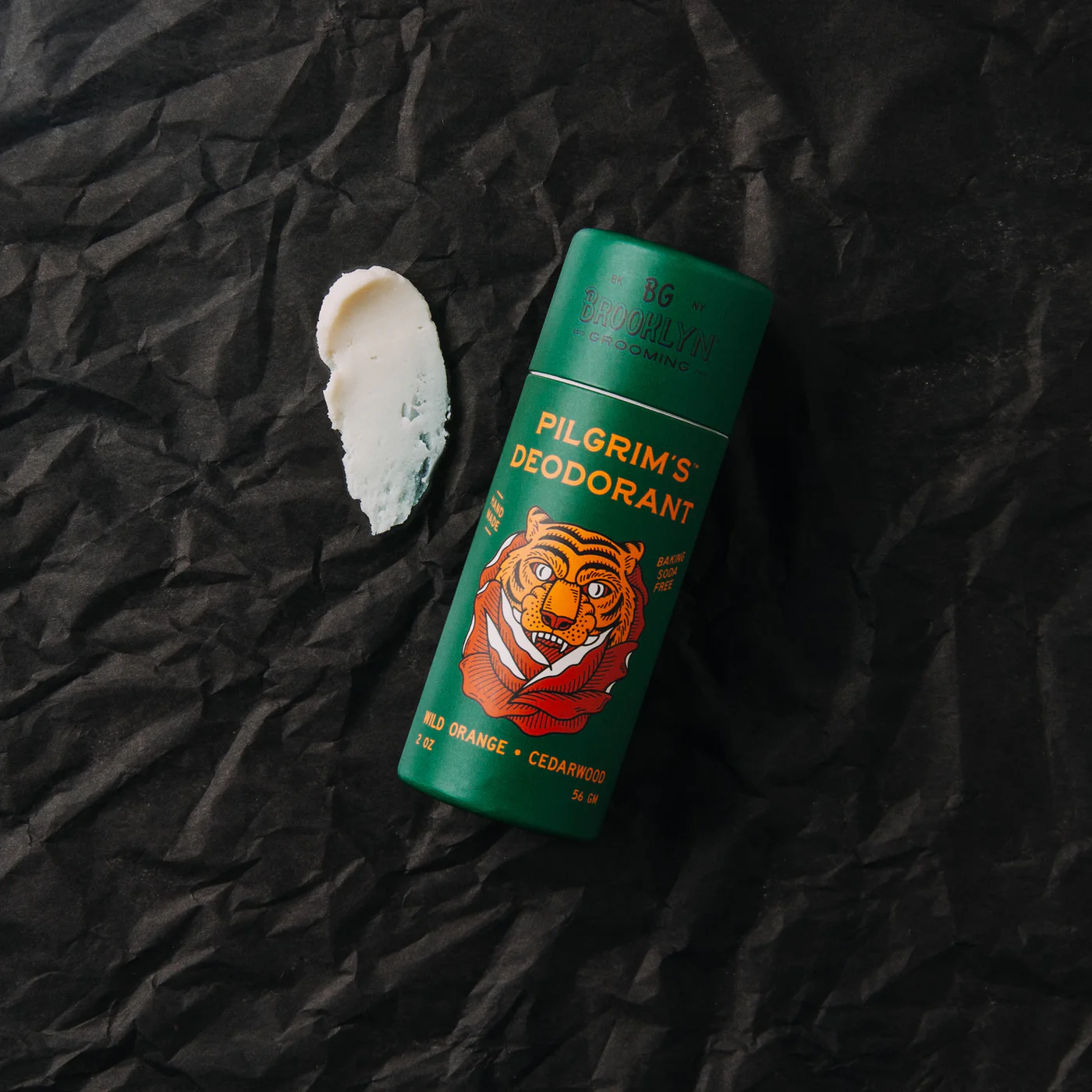 Pilgrim's deodorant bottle with tiger illustration on a black crumpled paper background