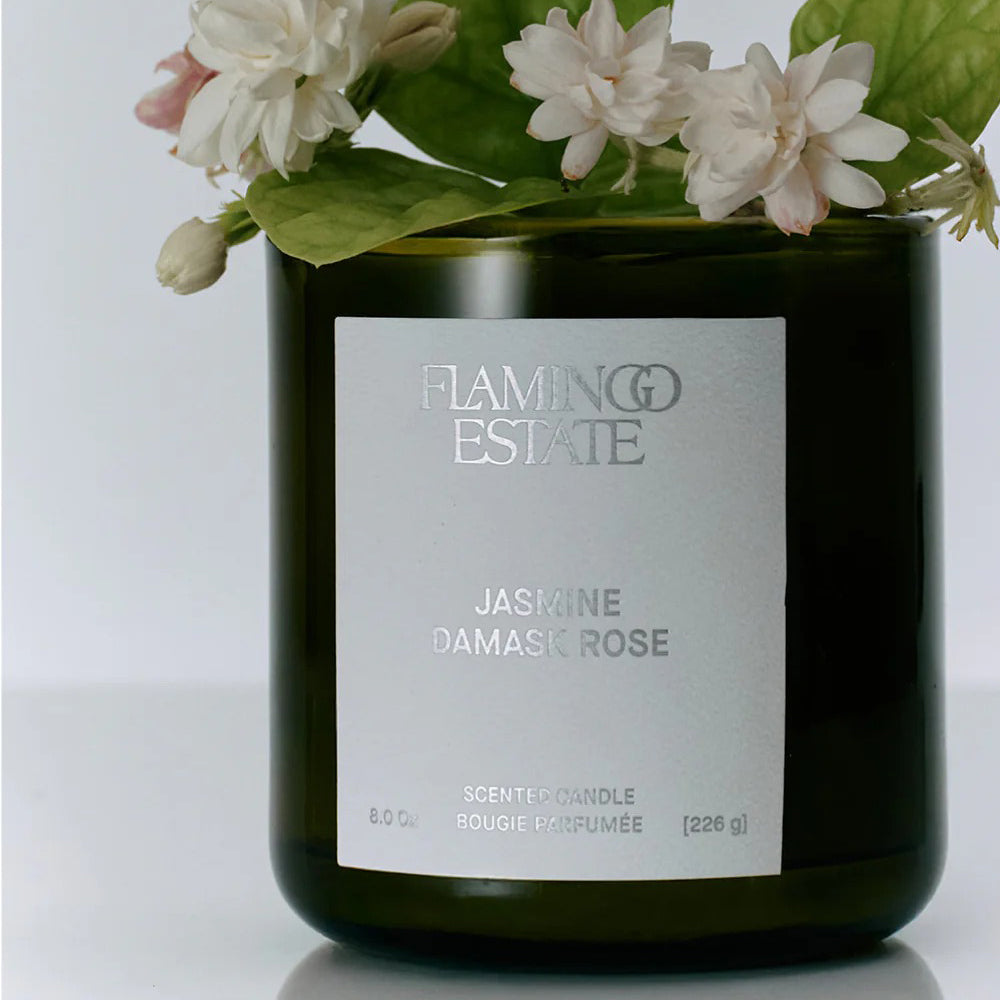 Candle with 'Flaming Estate' label and jasmine flowers on a white background