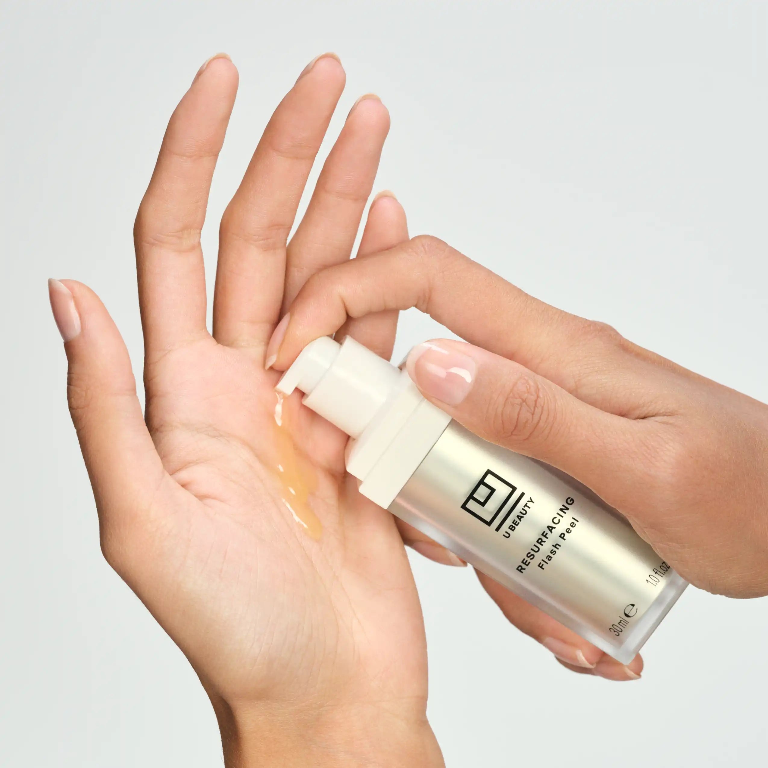 Hand holding a skincare product with visible brand on a neutral background