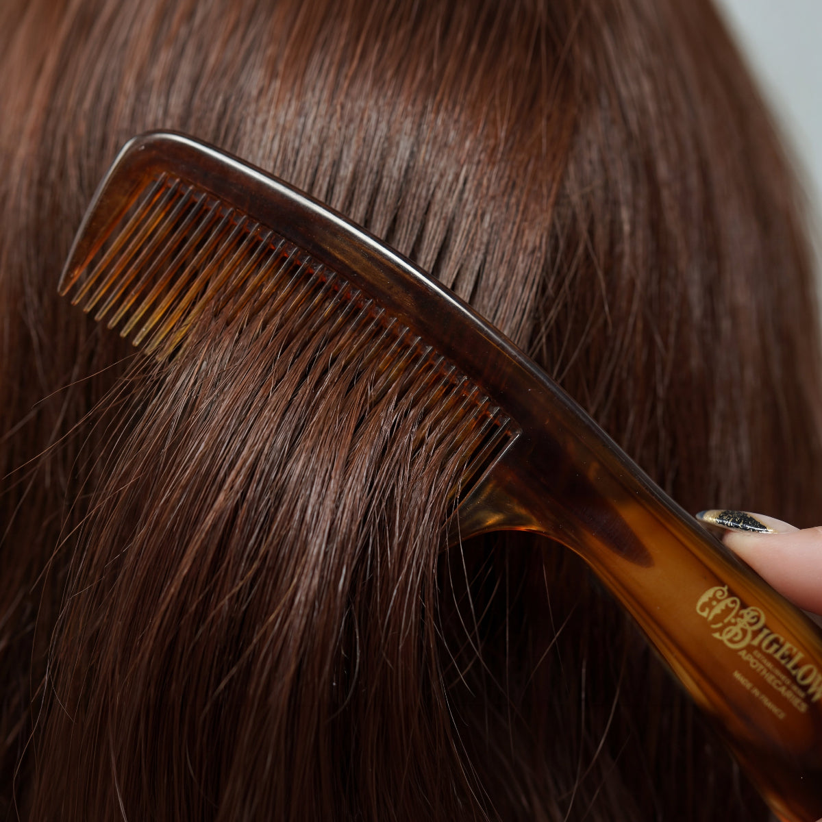 C.O. Bigelow Handle Comb brushing person's hair.