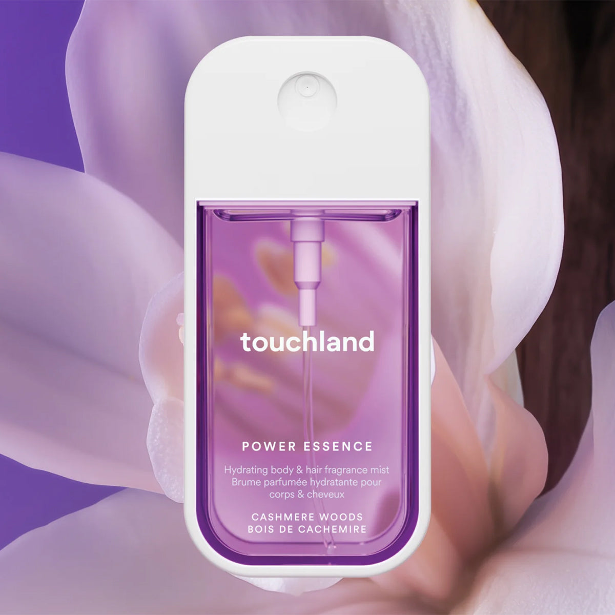 Touchland Power Essence Hydrating Body & Hair Mist - Cashmere Woods, featuring a white top and a purple translucent lower section, set against a soft-focus background of lavender flower petals.