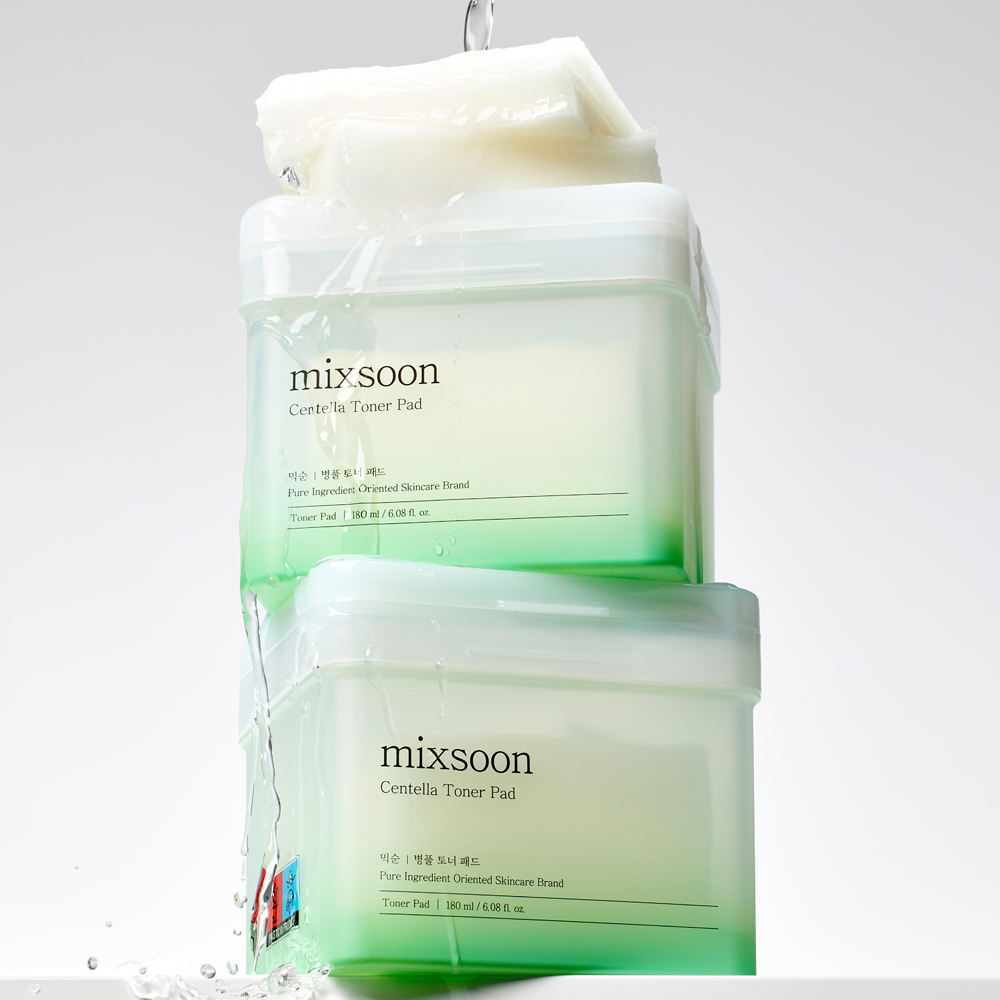 2 Mixsoon Centella Toner Pad containers stacked with water pouring on top of them on a white surface, in front of a white background
