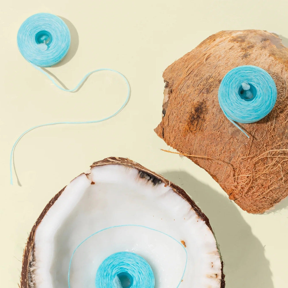 Coconut halves with cocofloss spools on a beige background