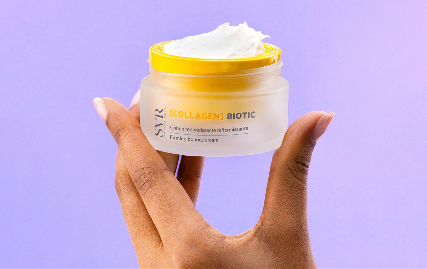 Person holding SVR Collagen Biotic Cream on a purple background.