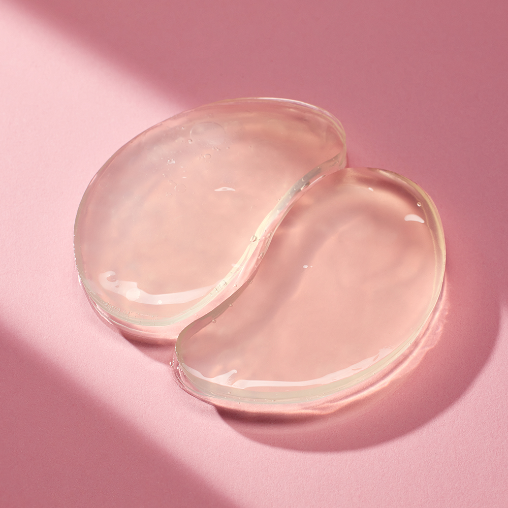 mixsoon Collagen Hydrogel Eye Patch out of packaging on a pink background with strong lighting