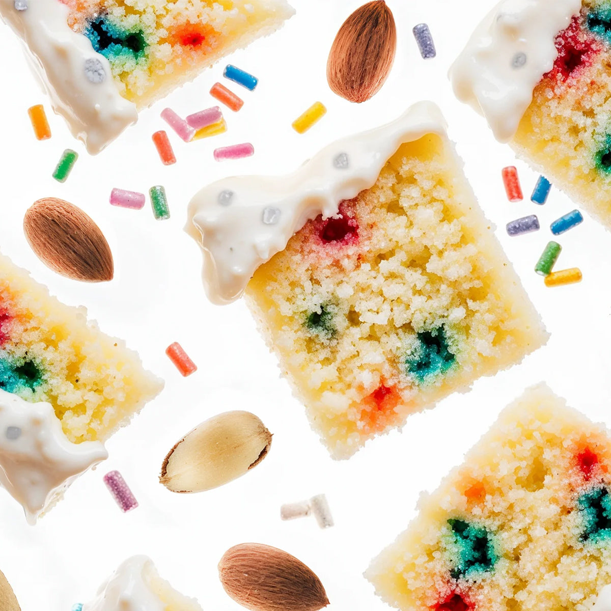 Square slices of a crumbly yellow cake or cookie with white icing and colorful sprinkles, scattered with whole almonds and candy pieces on a white background.