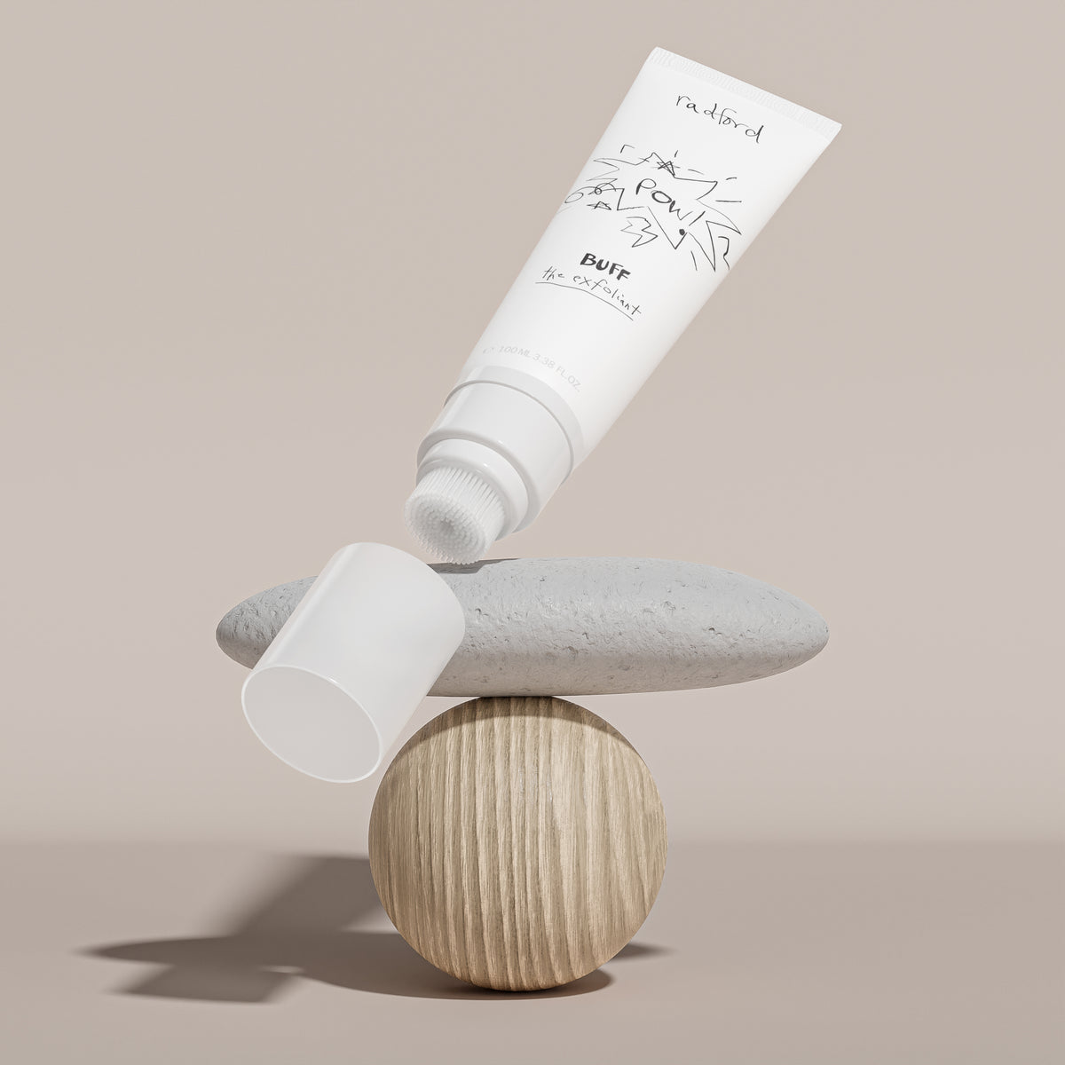 Tube of Radford Buff the Exfoliant on a balanced stone and wooden block with a neutral background