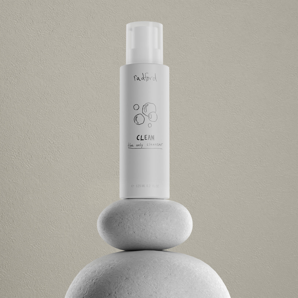 A white bottle of Radford Clean - the only cleanser stands centered on stacked smooth white stones against a textured light beige wall.