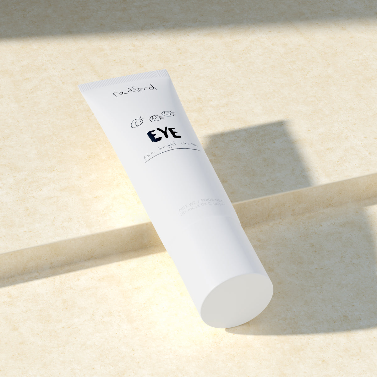 A white cosmetic squeeze tube of Radford Eye -the Bright Cream resting diagonally on a textured beige surface with soft shadows.
