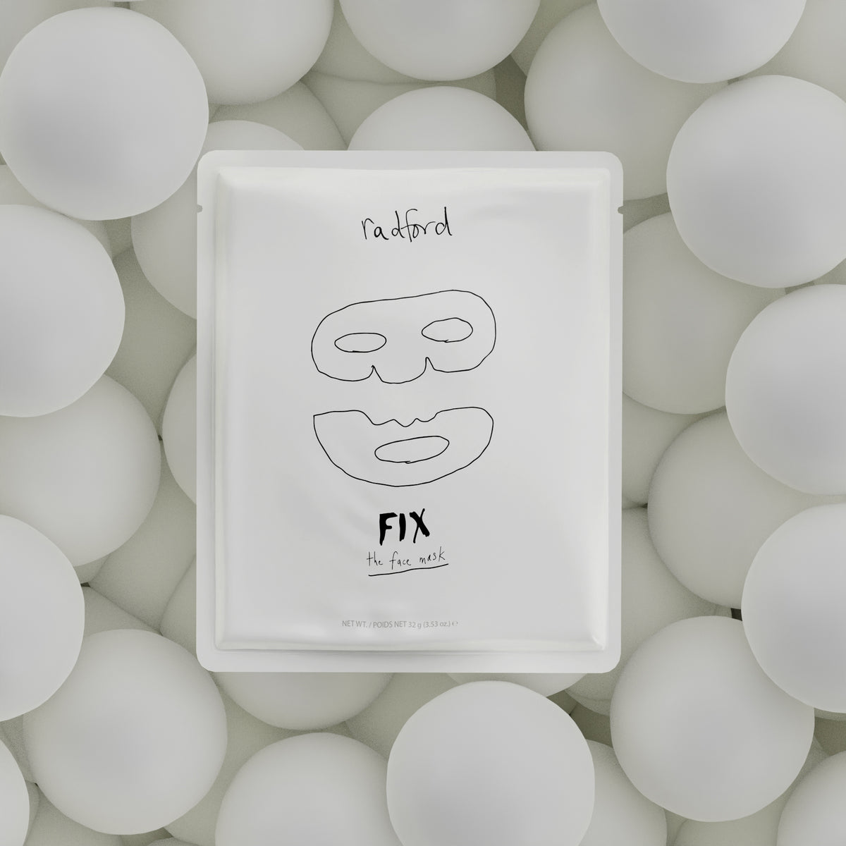 A white square packet for Radford Fix -the face mask, featuring a minimalist black line drawing of a face while centered on a bed of white spheres.