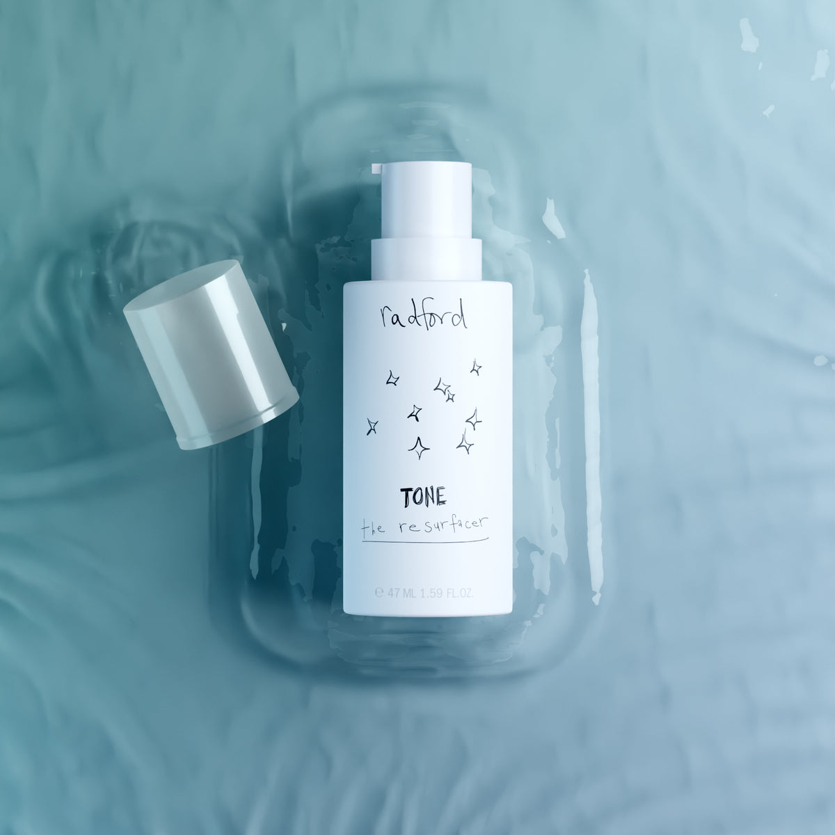 A bottle of Radford Tone the resurfacer skincare product with its cap off, resting on a textured light blue surface with water ripples.