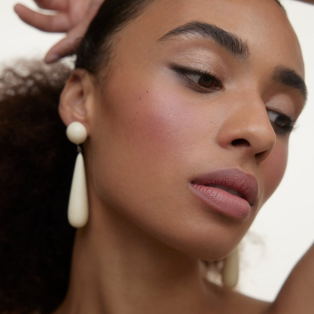 Closeup of woman's face wearing Wonderblush makeup products. 