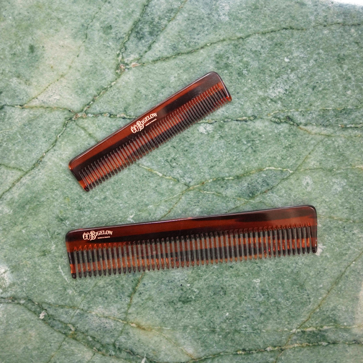 Two combs on a green marble surface