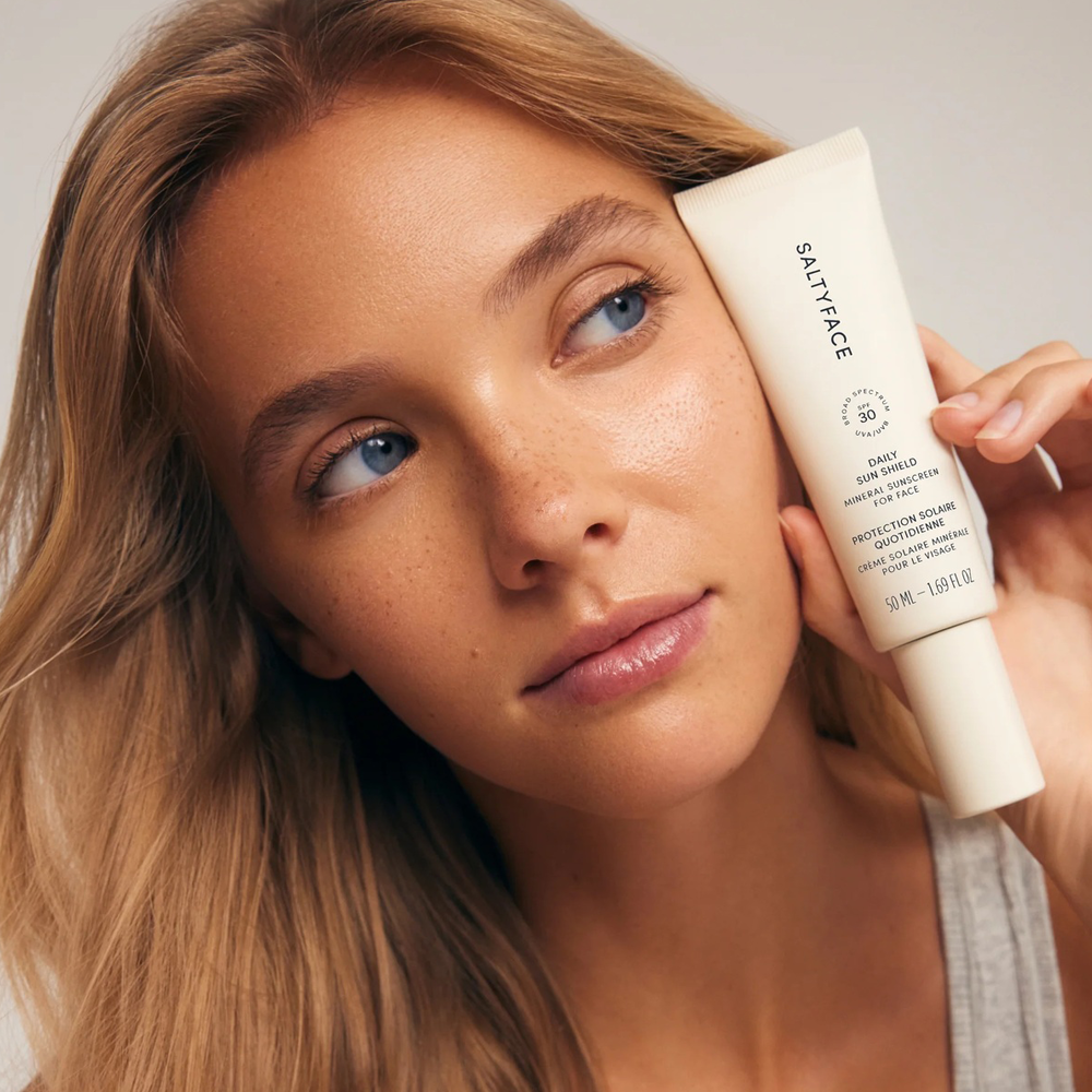 Woman holding a Saltyface skincare product near her face