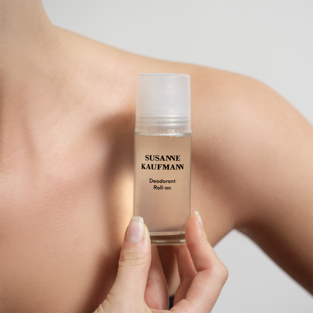 Woman holding Susanne Kaufmann Deodorant Roll-on in front of her shoulder