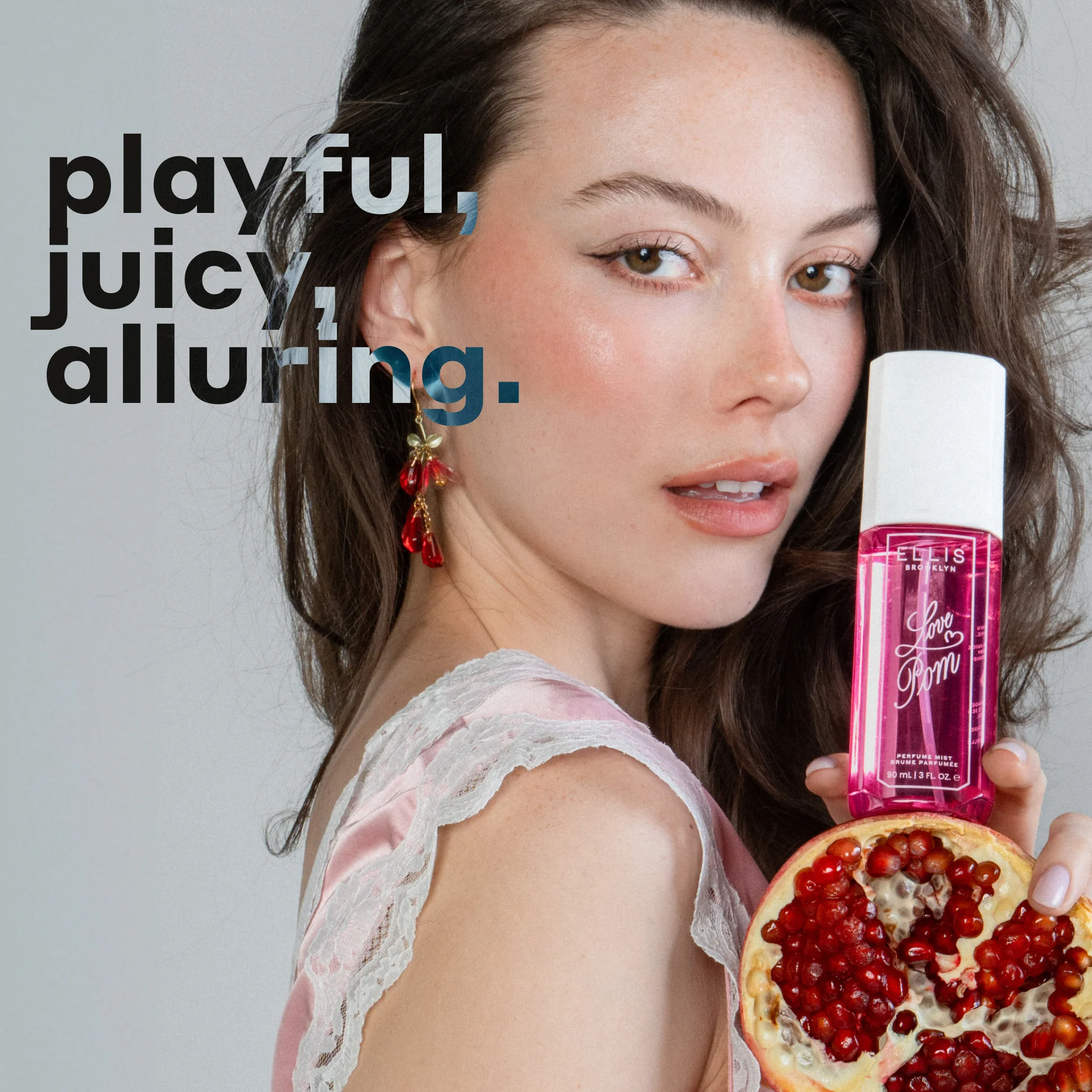 Woman holding a bottle of perfume next to a pomegranate with text describing the fragrance.