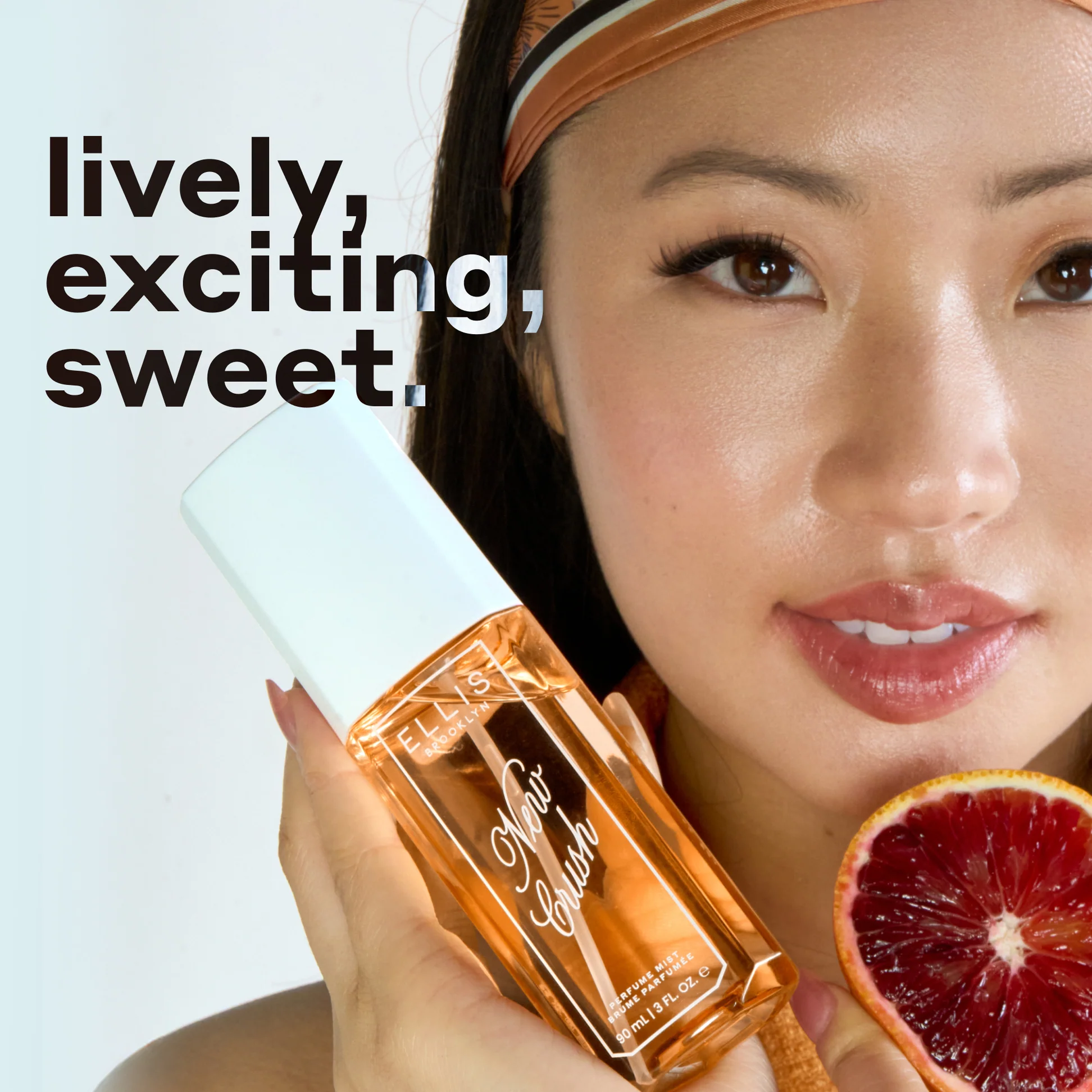 Woman holding New Crush bottle with a grapefruit half, text 'lively, exciting, sweet' on a light gray background.