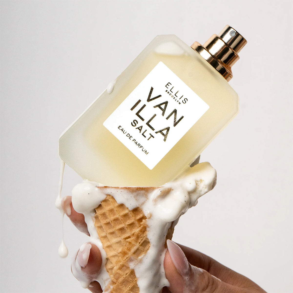 Perfume bottle labeled 'Vanilla Salt' held with an ice cream cone against a light background