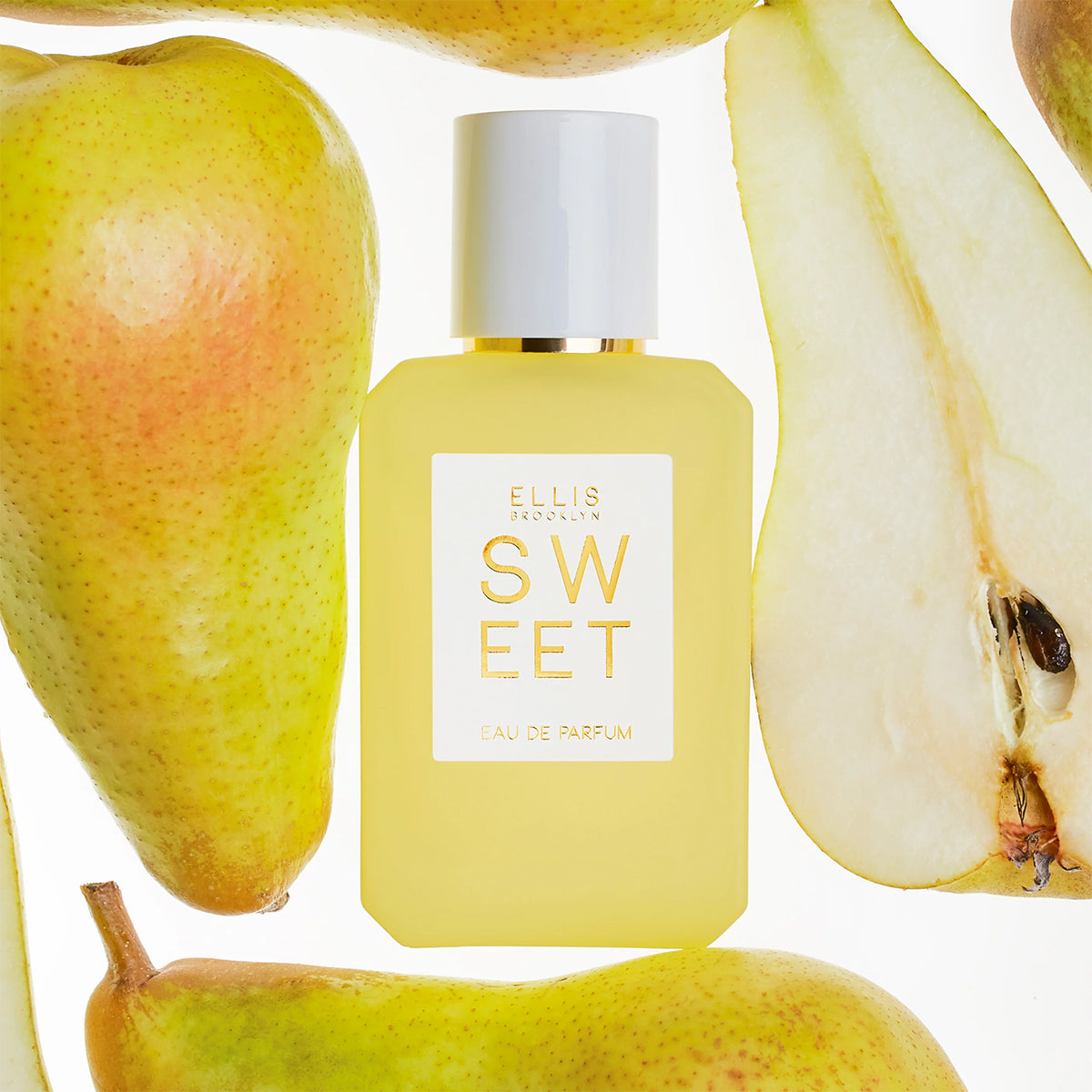 Perfume bottle labeled 'Sweet' by Ellis Brooklyn surrounded by pears on a white background