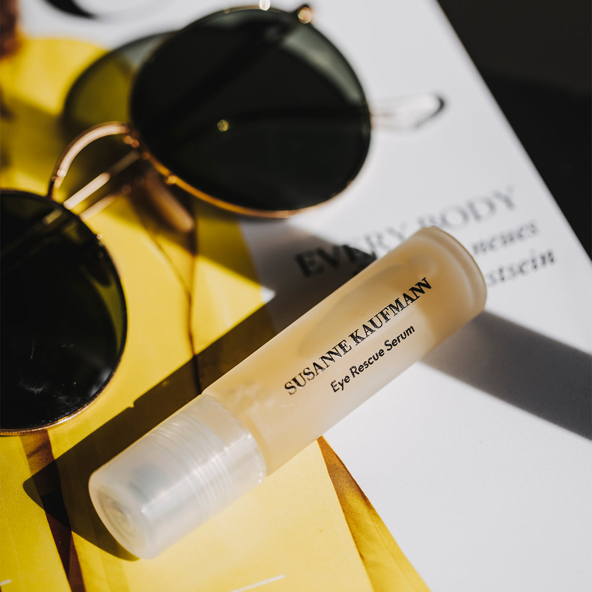 Suzanne Kaufman eye serum bottle with sunglasses on a magazine