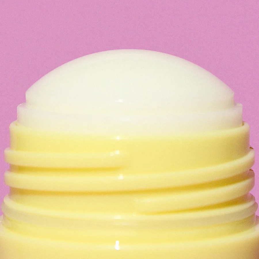 Yellow and white cylindrical container on a pink background