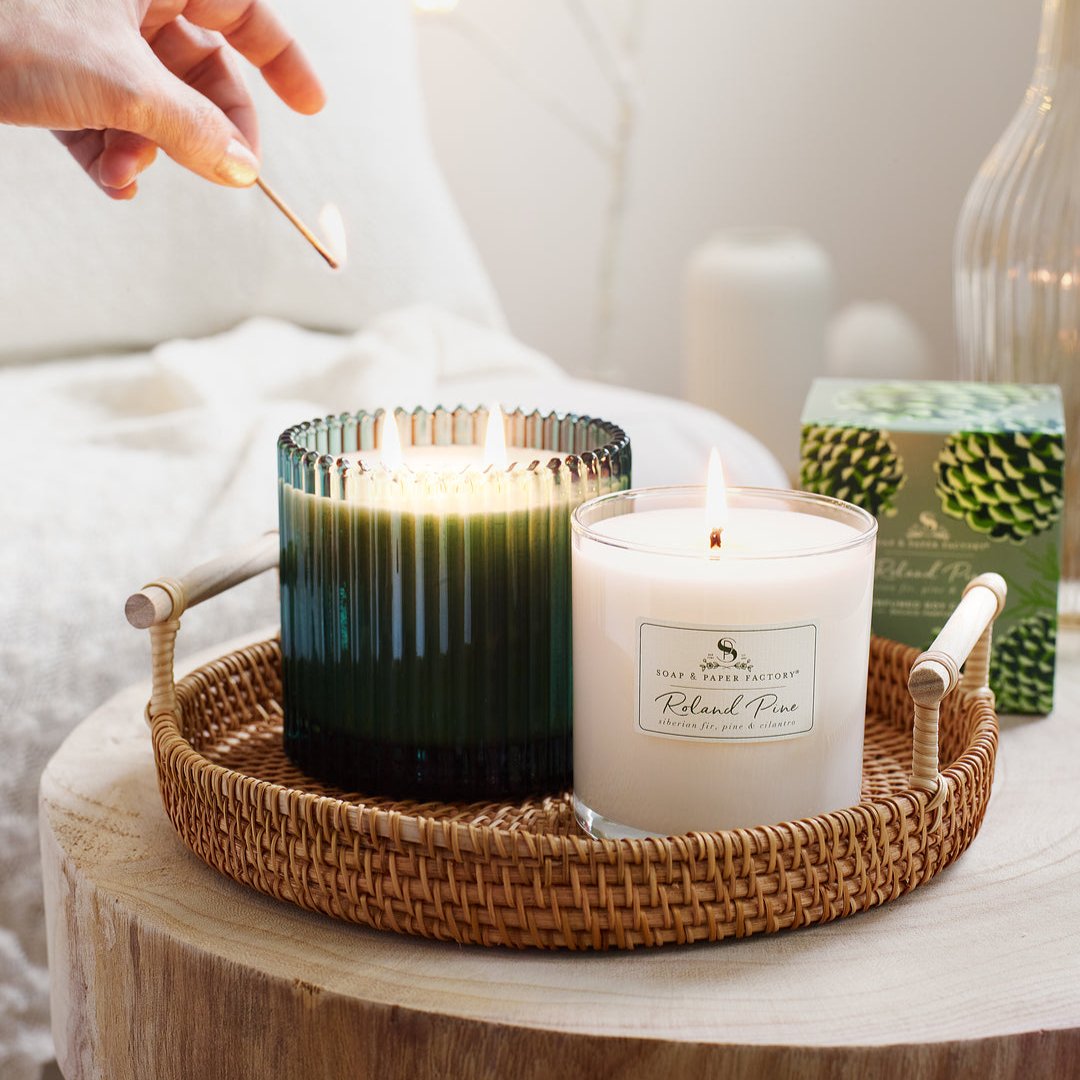 Person lighting 2 candles with a match on a coffee table. 