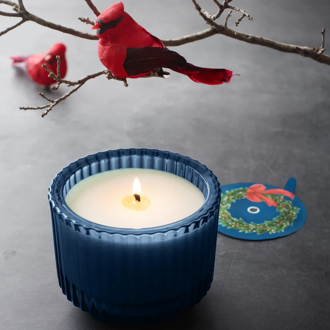 Roland Pine Candle in a blue holder with red cardinals on branches in the background