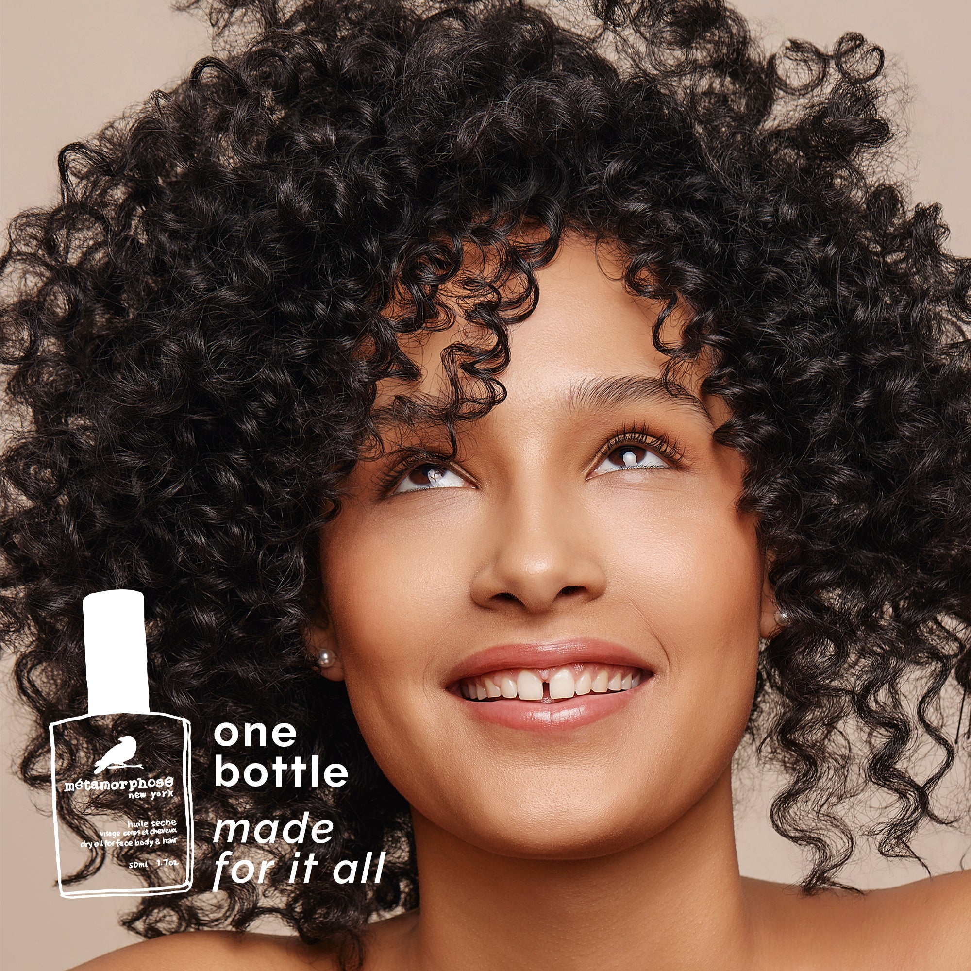 Woman with curly hair and a bottle of dry oil with text 'one bottle made for it all'.